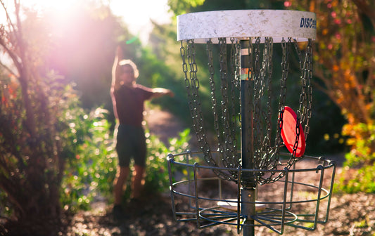 Person playing disc golf in a sunlit outdoor setting