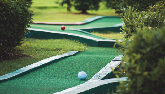 Close up of a mini golf (or "putt putt") course with two golf balls on different holes of the course.